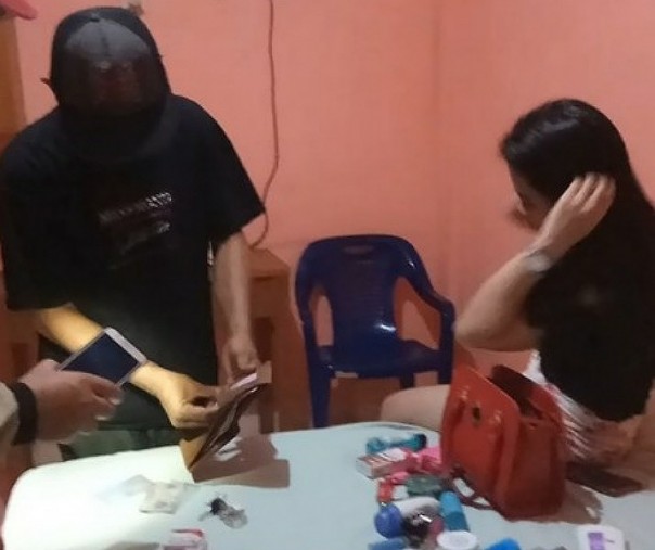 Petugas kepolisian saat menggeledah tas milik salah seorang wanita yang berbuat mesum dengan pria hidung belang di salah satu kamar SCH Hotel, beberapa waktu lalu. Foto: Riau1.