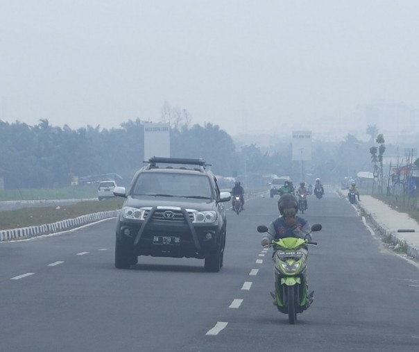 Pengendara motor menggunakan masker saat kabut asap masih menyelimuti Kota Pekanbaru, Kamis (22/8/2019). Foto: Surya/Riau1.