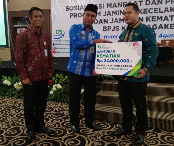 Plt Kepala Dinkes Pekanbaru M Amin menyerahkan santunan secara simbolis kepada keluarga Ahmad Basuki, mantan THL Dinas PUPR, Kamis (22/8/2019). Foto: Surya/Riau1.