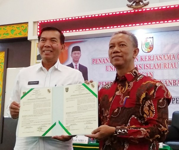 Wali Kota Pekanbaru Firdaus bersama Rektor UIR Syafrinaldi melihatkan MoU yang telah ditandatangani, Rabu (11/9/2019). Foto: Surya/Riau1.