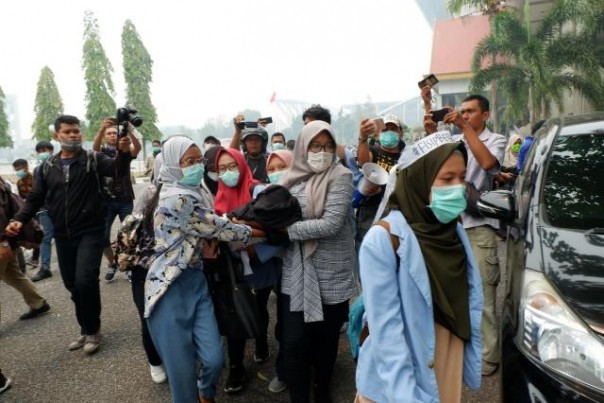 Mahasiswi Universitas Riau pingsan karena sesak nafas saat demo memprotes kabut asap semakin tebal di depan Kantor Gubernur Riau, Kamis. 