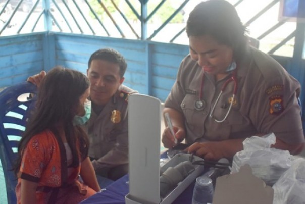 Kasatlantas Polresta Pekanbaru, AKP Emil Eka Putra bercengkrama dengan salah seorang anak yang ikut pengobatan gratis