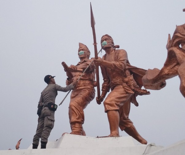 Satpol PP Provinsi Riau melepas masker yang melekat monumen perjuangan gedung daerah (Foto: Zar/Riau1.com)