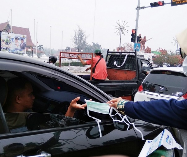 Seorang mahasiswi membagikan masker kepada para pengendara di pertigaan Gedung Daerah Riau, Sabtu (14/9/2019). Sampai saat ini, kualitas udara di Pekanbaru masih tidak sehat.