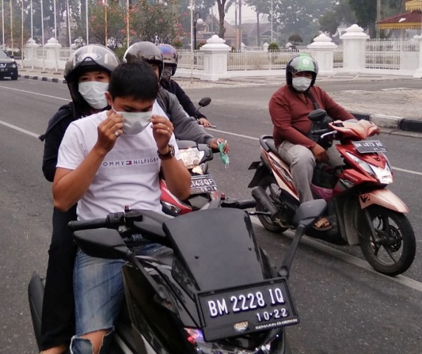 Seorang pengendara sepeda motor mengenakan masker sat berhenti di pertigaan Gedung Daerah Riau, Jalan Diponegoro, Pekanbaru, Sabtu (14/9/2019). Terlihat latar belakang kabut asap tebal. Foto: Surya/Riau1.