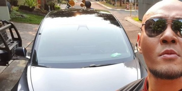 Deddy Corbuzier berselfie dengan latar Tesla Model 3 miliknya