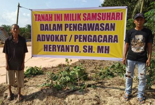 Salah seorang warga Talang Mandi memasang spanduk di tanah miliknya yang terkena proyek jalan tol Kandis-Dumai