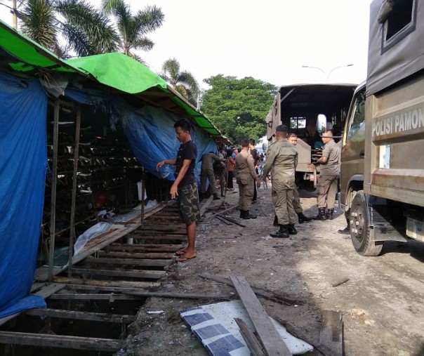 Petugas Satpol PP Pekanbaru saat membongkar lapak dagangan yang menutupi drainase di Jalan Soebrantas. Foto: Surya/Riau1.