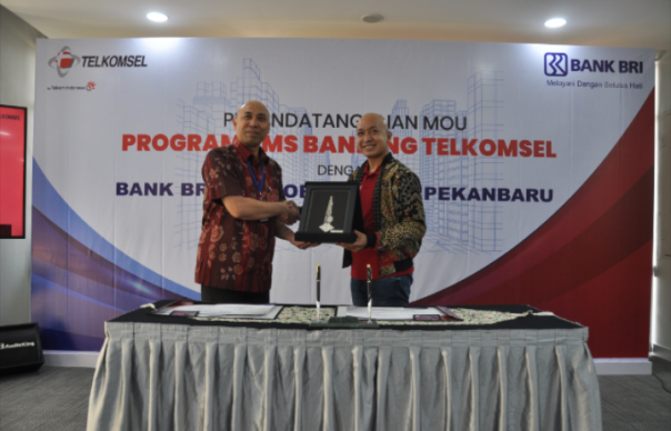 Pimpinan Kantor Wilayah Pekanbaru BRI Harry Gusti Utama (kiri) dan General Manager Digital Products Sales Sumatera Telkomsel Yudi Chahyadi Anwar (kanan) mengesahkan Program Kerja Sama SMS Banking Telkomsel dan Bank Rakyat Indonesia.