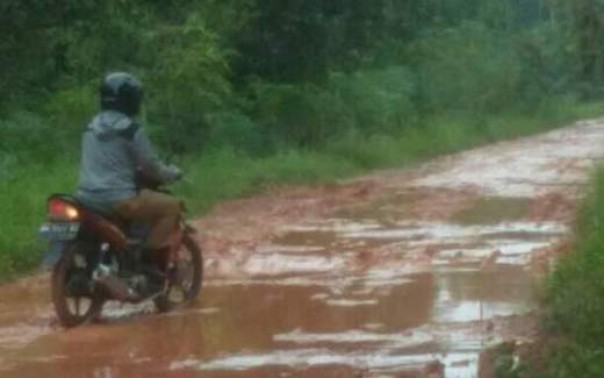 Salah seorang warga melwati jalan yang berubah menjadi kubangan lumpur di Kelurahan Bagan Keladi, Kota Dumai