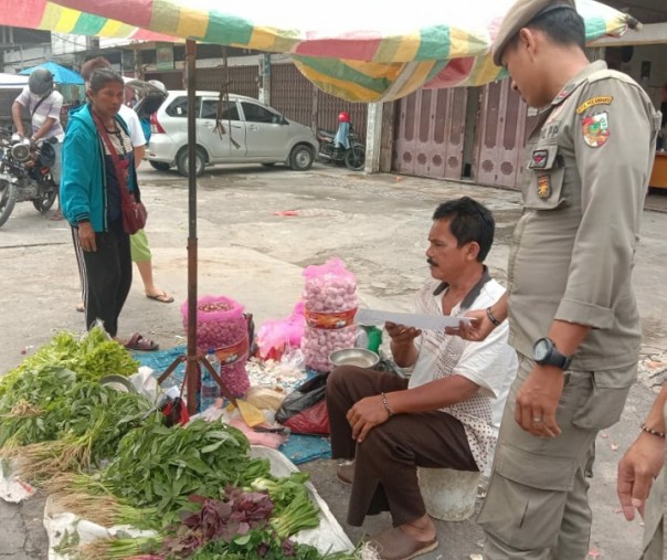 Petugas Satpol PP Pekanbaru memberikan surat peringatan kepada salah seorang pedagang kaki lima di seputar Pasar Sukaramai, Rabu (23/10/2019). Foto: Satpol PP Pekanbaru.