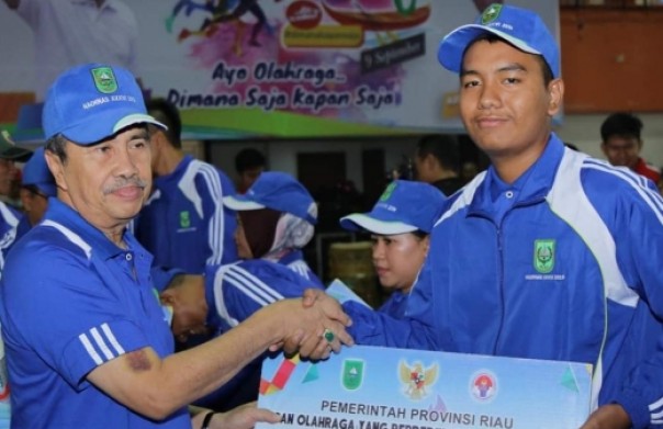Gubernur Riau, Syamsuar memberikan bonus secara simbolis kepada salah seorang atlet Riau yang berprestasi saat peringatan Haornas