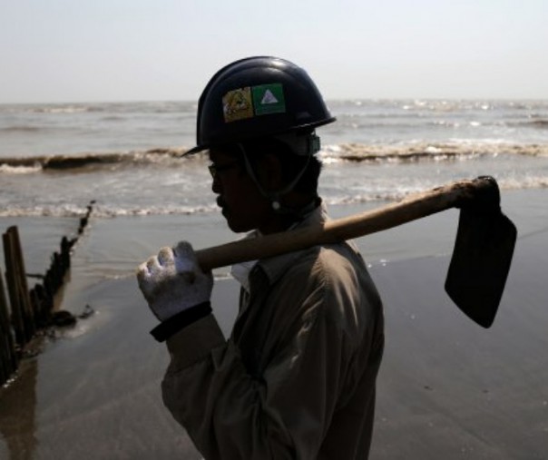 Petugas Oil Spill Combat Team (OSCT) menggunakan baju Tyvex, helmet, sarung tangan dan membawa cangkul saat membersihkan tumpahan minyak. Foto: Kumparan.com.