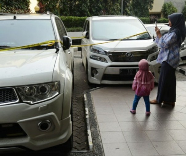 Seorang calon jamaah memotret sejumlah mobil sitaan polisi yang merupakan aset milik dua tersangka pemilik agen perjalanan First Travel. Foto: Tempo.co.