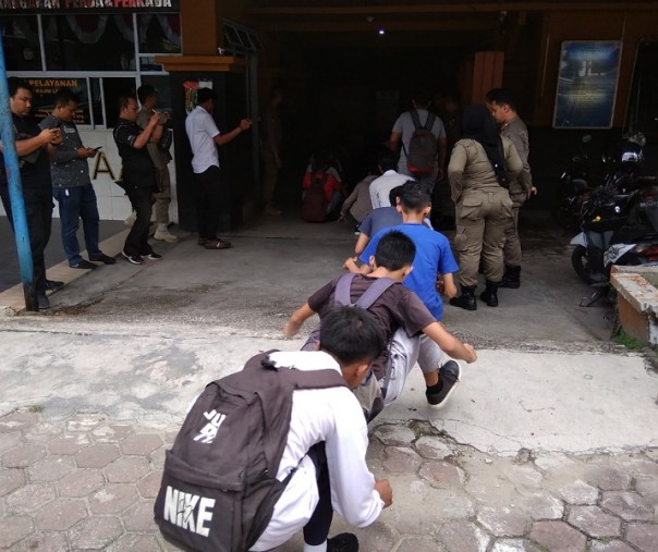 Sebanyak 33 pelajar bolos sekolah berjalan jongkok di halaman Kantor Satpol PP Pekanbaru, Senin (18/11/2019). Foto: Surya/Riau1.