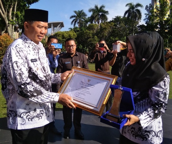 Wali Kota Pekanbaru menyerahkan penghargaan kepada Kepala SMPN 4 Pekanbaru Rukiah. Foto: Surya/Riau1.