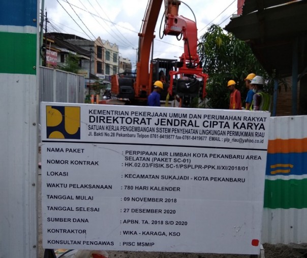 Para pekerja sedang mengerjakan proyek IPAL di Jalan KH Ahmad Dahlan Pekanbaru, Senin (2/12/2019). Terlihat papan dipajang tentang nilai dan lama pengerjaan proyek ini. Foto: Surya/Riau1.
