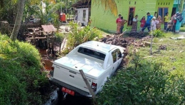 Tampak mobdin milik Pemkab Bengkalis terperosok ke dalam parit hingga nyaris menabrak rumah warga di Desa Penebal