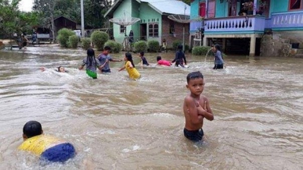 Anak-anak bermain di genangan banjir
