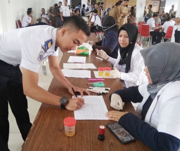 Salah seorang petugas Dishub Riau menyerahkan hasil urine kepada dokter dari BNNP Riau di Aula Kantor Satpol PP Riau, Senin (23/12/2019). Foto: Surya/Riau1.