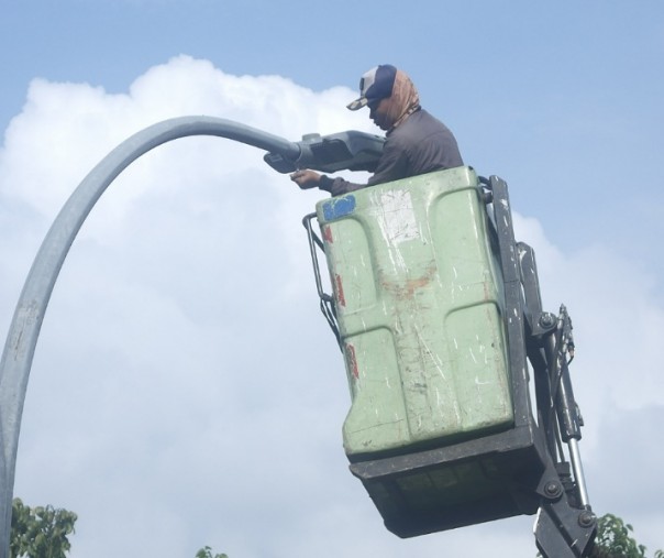 Seorang pekerja sedang mengganti bola lampu jalan di depan Sudirman Square Jalan Jenderal Sudirman. Foto: Surya/Riau1.