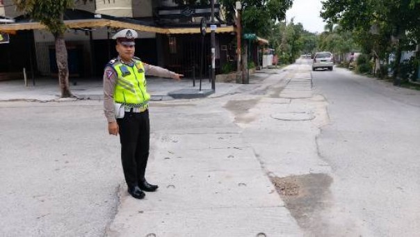 Salah seorang Polantas menunjukkan jalan yang rusak akibat proyek IPAL di Kecamatan Sukajadi