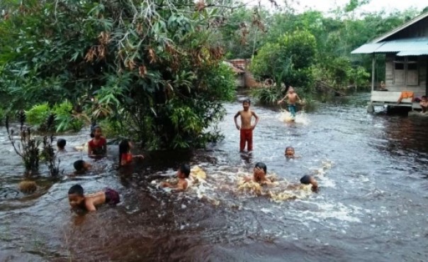 Anak-anak bermain di genangan banjir