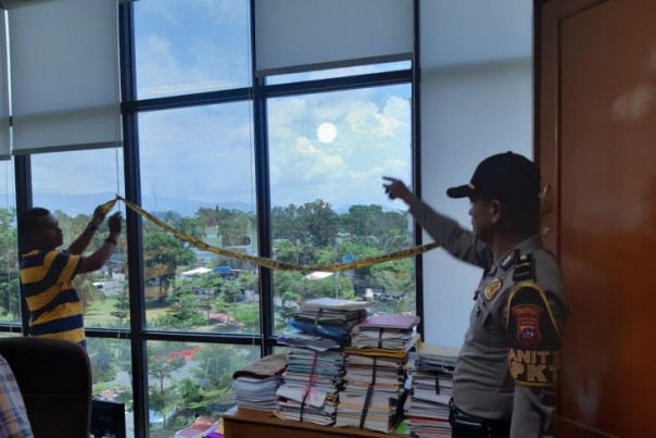 Polisi memeriksa kaca gedung kampus Universitas Negeri Padang yang kena peluru nyasar, Selasa. 