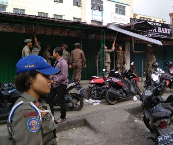 Petugas Satpol PP Pekanbaru saat mencopot papan nama toko emas sebelum terjadi bentrokan dengan pedagang pada 25 Februari lalu. Foto: Surya/Riau1.