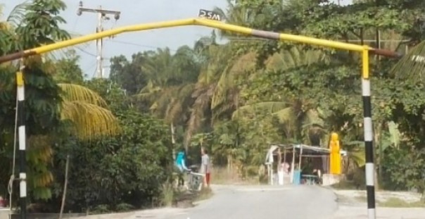 Salah satu ruas jalan aspal yang baru selesai dibangun di Desa Rimpian, yang semula dipasang portal sesuai kelas jalan, kini terlihat portal tersebut sudah bengkok bagian atas. Diduga, hal itu dilakukan agar mobil over tonase bisa melintas. Foto diabadikan, Senin 2 Maret 2020.