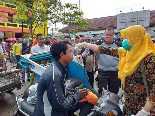 Bupati Inhu Yopi Arianto (dua kanan) memperhatikan petugas kesehatan yang tengah memeriksa suhu tubuh tukang becak di Pasar Rakyat Rengat, Kamis 19 Maret 2020 pagi. Saat blusukan itu Bupati Yopi juga memberikan edukasi kepada warga yang berada di pasar tersebut.