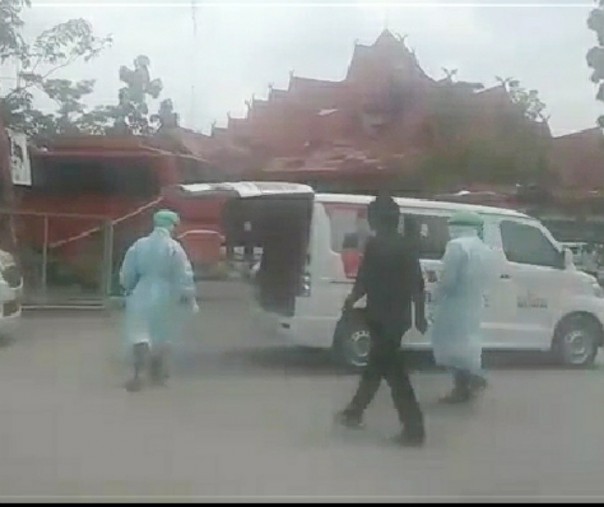 Seorang pria digiring petugas medis ke mobil ambulans karena demam dan batuk di loket bus Terminal BRPS Pekanbaru, Sabtu (28/3/2020). Foto: Tangkapan layar video.