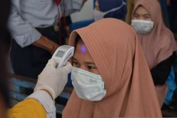 Ilustrasi petugas memeriksa suhu tubuh terkait antisipasi virus corona.  