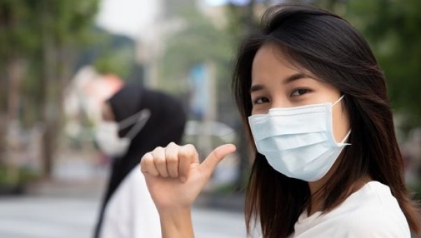 Ilustrasi perempuan menggunakan masker cegah penularan virus corona. 