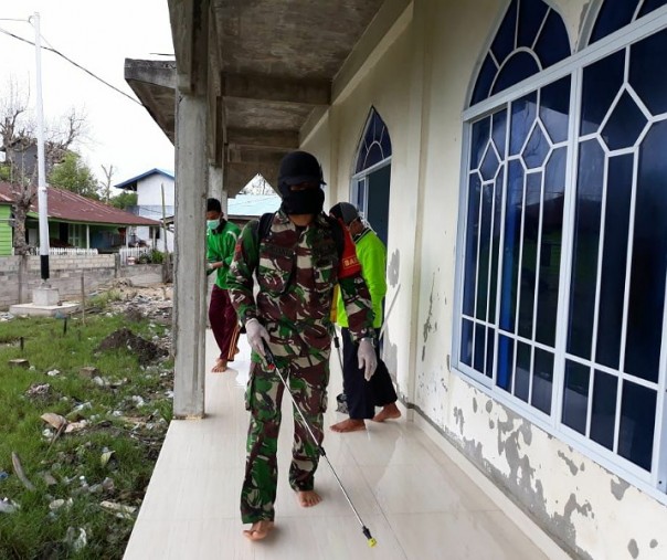 Babinsa Labuhan Bilik, Kecamatan Teluk Meranti, Kabupaten Pelalawan dibantu warga setempat melakukan penyemprotan cairan disinfektan ke fasilitas umum dan permukiman warga, Minggu (5/4/2020). Foto: Istimewa.