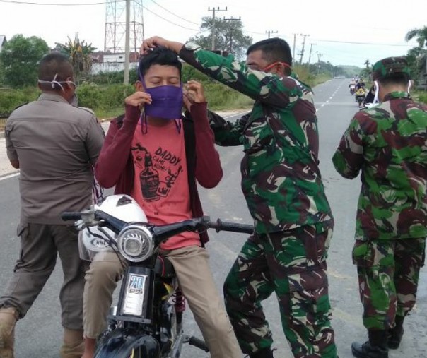 Personel Koramil 12/XIII Koto Kampar, Kabupaten Kampar, Riau, memasangkan masker kain ke pengendara. Foto: Istimewa.