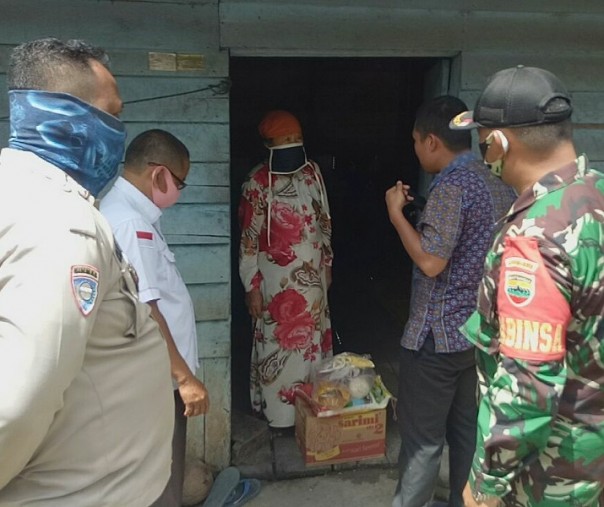 Babinsa Koramil 01 Bangkinang Sertu Cipto Widodo dan anggota Bhabinkamtibmas serta Manajer PLTA Koto Panjang saat menyerahkan bantuan sembako ke salah satu rumah warga di Desa Merangin, Kuok, Kampar, Jumat (1/5/2020). Foto: Istimewa.