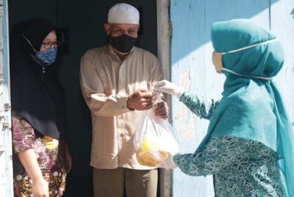 Ketua TP PKK Siak, Rasidah Alfedri saat memberikan bantuan kepada masyarakat dhuafa