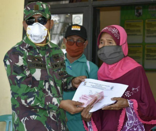 Babinsa Koramil 04 Pangkalan Kuras Kodim 0313 Kampar Serma Riswanto saat menyerahkan BLT DD secara simbolis ke salah seorang warga, Jumat (8/5/2020). Foto: Istimewa.