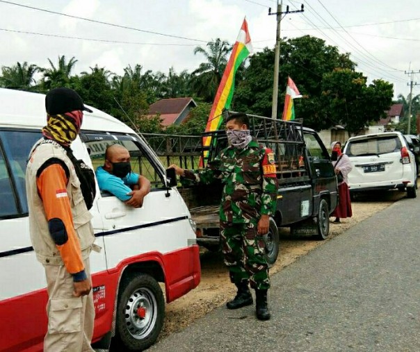 Babinsa Batu Langkah Besar Koptu Anjas saat memberikan imbauan soal bahaya virus corona kepada para pengendara yang akan masuk ke Kabupaten Rokan Hulu, Selasa (19/5/2020). Foto: Istimewa.