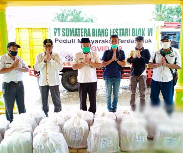 Humas PT SRL Estate Bayas Albert Sianipar menyerahkan paket bantuan bahan pokok yang diterima langsung oleh Camat Kempas, disaksikan Lurah Kempas Jaya, Kades Pekantua dan Kades Bayas Jaya