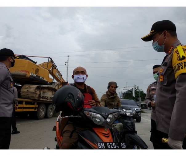 Kombes Nandang memberikan warga masker bertulis jangan mudik, saat meninjau posko di jalur lintas barat Kota Pekanbaru.