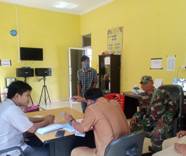 Babinsa Pangkalan Tampoi Pelalawan Serda Indra Gunawan saat melakukan komunikasi sosial dengan perangkat desa, Rabu (27/5/2020). Foto: Istimewa.