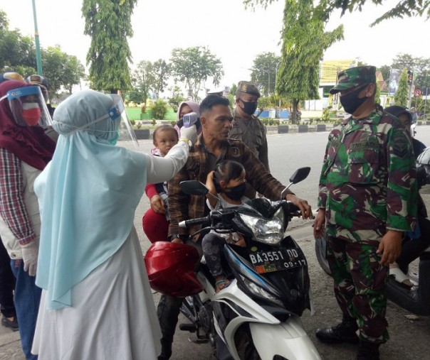 Babinsa Sertu S Tanjung mendampingi petugas Puskesmas di depan Pasar Kuok, Kampar, Jumat (29/5/2020). Foto: Istimewa.