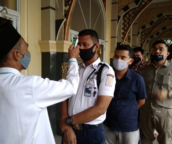 Petugas Masjid Ar Rahman Pekanbaru mengukur suhu tubuh para jemaah yang hendak melaksanakan salat Jumat (29/5/2020). Foto: Surya/Riau1.