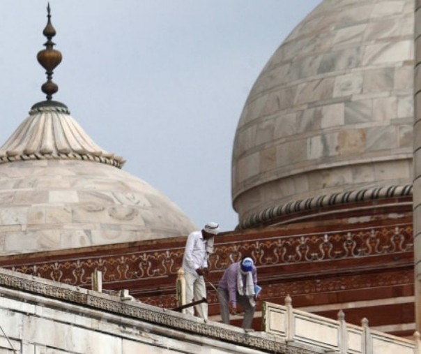 Pekerja memperbaiki pagar Taj Mahal yang rusak akibat badai. Foto: AFP.