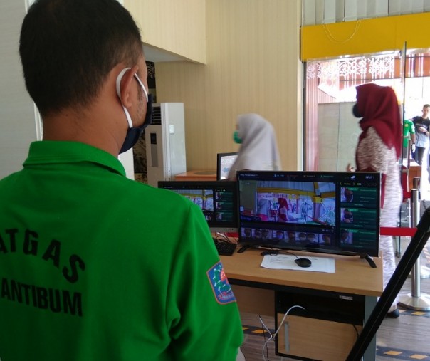 Petugas Satpol PP Pekanbaru saat memantau suhu tubuh pengunjung Mal Pelayanan Publik melalui layar termometer scanner, Jumat (5/6/2020). Foto: Surya/Riau1.