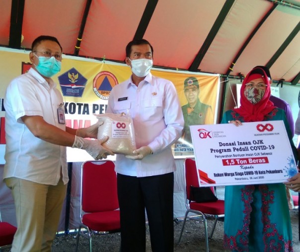 Kepala OJK Riau Yusri menyerahkan bantuan beras secara simbolis kepada Wali Kota Pekanbaru Firdaus di halaman MPP, Jumat (5/6/2020). Foto: Surya/Riau1.