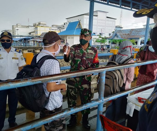Babinsa Teluk Dalam Sersan Hendra bersama anggota Polsek Kuala Kampar dan petugas Dishub Pelalawan mengecek suhu tubuh penumpang di Pelabuhan Penyalai, Sabtu (6/6/2020). Foto: Istimewa.