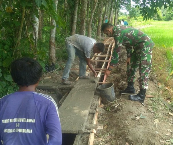 Babinsa Empat Balai Serda Supriadi membantu warga membangun saluran irigasi, Rabu (24/6/2020). Foto: Istimewa.